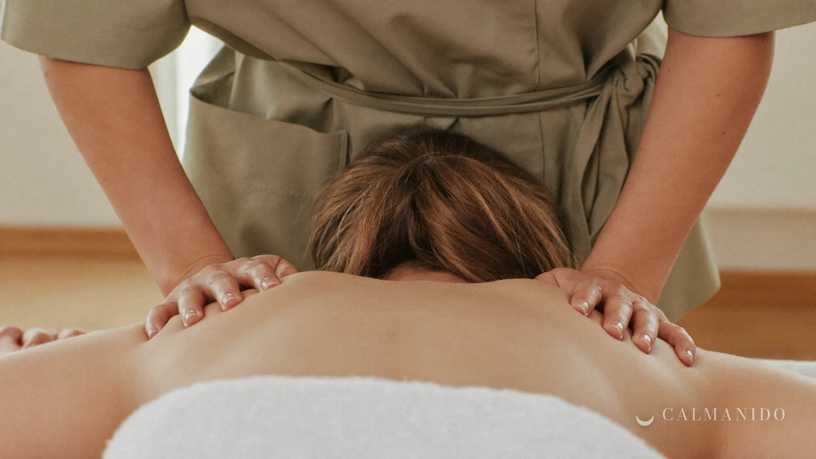 A therapist's hands massaging a client's shoulders